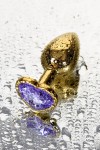Золотистая анальная втулка с фиолетовым кристаллом-сердечком - 7 см. фото 2 — pink-kiss